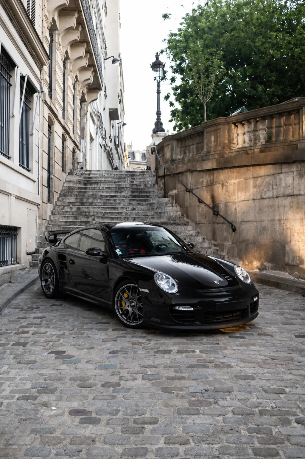 Black Porsche 997 GT2 beside stone steps in Paris